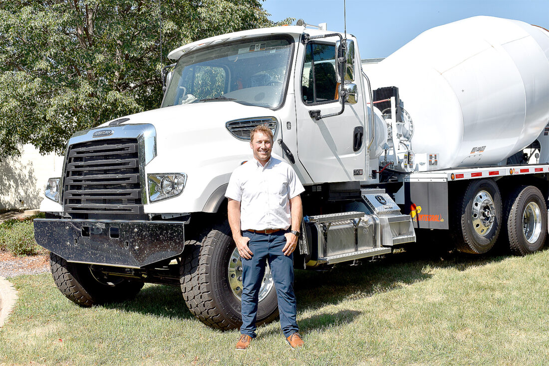  SpecSys, Inc. President Tallen Wald stands with some of the brand new concrete mixer trucks the plant is building. 
